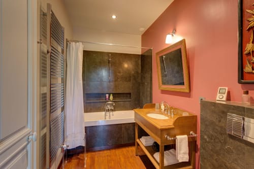 Salle de bain élégante au Château d'Alexis de Tocqueville avec murs corail, meuble-lavabo en bois et douche carrelée.