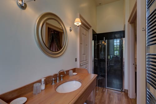 Salle de bain élégante au Château d'Alexis de Tocqueville avec vasque en bois, miroir rond et douche à l'italienne