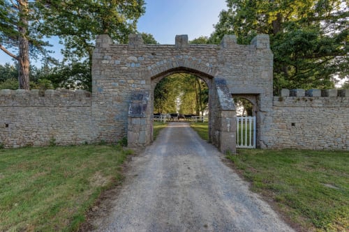 Stone gatehouse entrance with arched passages at Château d'Alexis de Tocqueville in Tocqueville, France