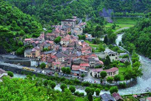 Vue aérienne d'un village niché dans la vallée de Mercantour avec rivière et montagnes verdoyantes