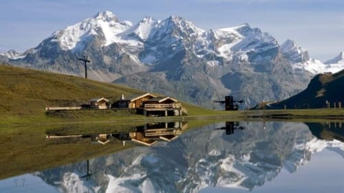 Montagnes alpines se reflétant dans une eau calme près d'un refuge rustique à Saint-Dalmas-le-Selvage, France