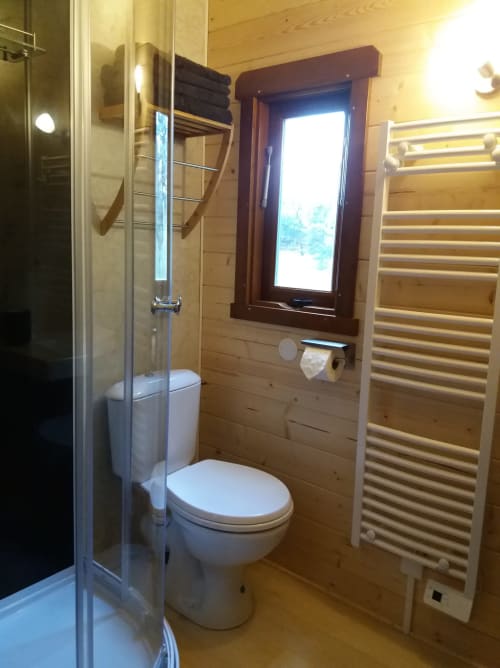 Modern wooden bathroom at Belloréade glamping refuge in Belloc with glass shower, toilet, and heated towel rack
