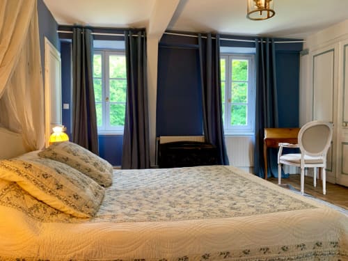 Spacieuse chambre triple à La Tour Blanche B&B à Forest-Montiers avec grand lit, murs bleu azur, rideaux épais et vue sur le jardin