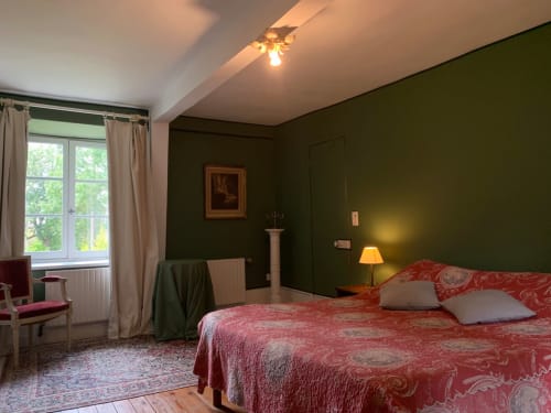Chambre élégante à La Tour Blanche, avec literie motifs rouges, murs vert olive et grandes fenêtres