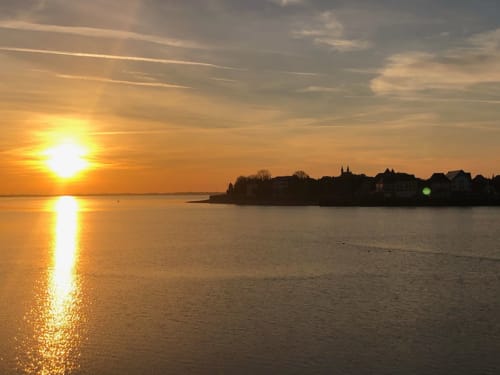 Coucher de soleil sur la baie de Somme près du gîte La Tour Blanche à Forest-Montiers, France, avec bâtiments historiques en silhouette
