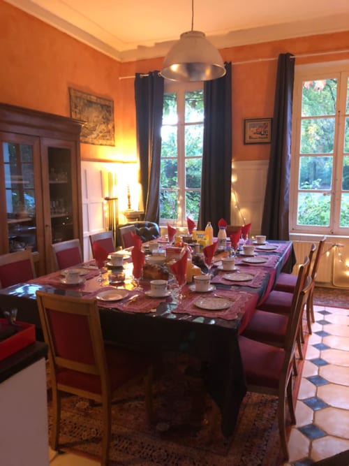 Élégante salle à manger de La Tour Blanche avec murs orangés, table dressée, chaises rouges et vue sur le jardin
