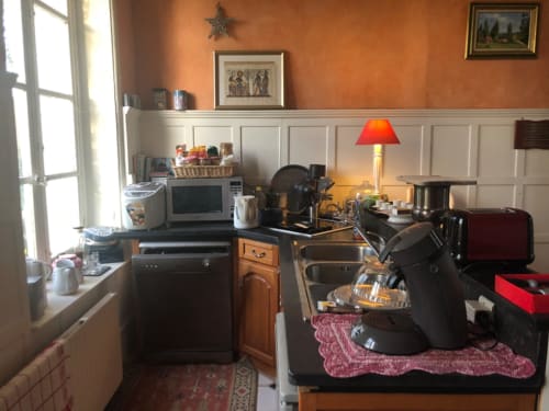 Petite cuisine du gîte La Tour Blanche à Forest-Montiers : murs orangés, lambris blanc et appareils rétro