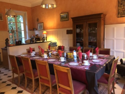 Élégante salle à manger de La Tour Blanche avec murs orangés, table dressée et mobilier en bois à Forest-Montiers