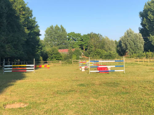 Carrière équestre du gîte La Tour Blanche à Forest-Montiers avec obstacles colorés et prairie verdoyante