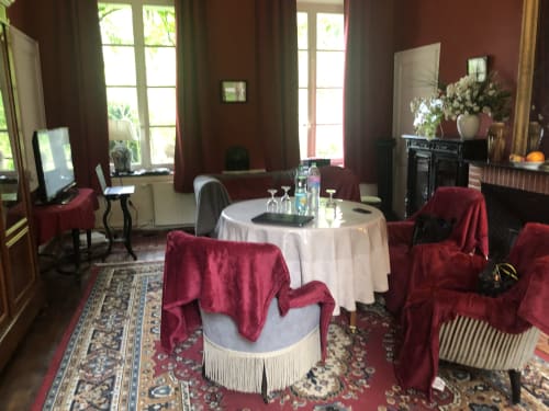Élégante salle de réunion à La Tour Blanche avec table ronde, chaises bordeaux et grandes fenêtres donnant sur Forest-Montiers