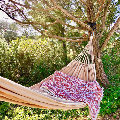 Beige hammock with red patterned blanket hanging from tree at Casa Serena villa in Porto Pollo, Corsica