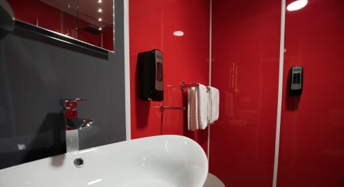 Bany modern de color vermell a l'Hôtel Rocade Pamiers amb lavabo blanc, portaestovals i dispensadors de sabó