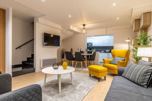 Espace de vie ouvert et moderne à l'Hôtel Au Bon Coin à Biarritz avec fauteuils jaunes, table à manger et cuisine