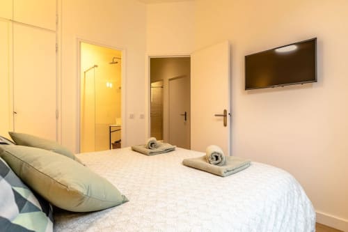 Chambre moderne de l'Hôtel Au Bon Coin à Biarritz avec lit, salle de bains, télévision écran plat et éclairage chaleureux