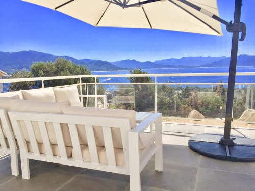 White lounge chairs with umbrella overlooking blue sea and mountains at Villas Marincelu, Porto Pollo