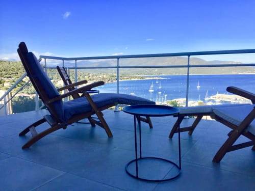 Oceanview terrace at Villas Marincelu with lounge chairs overlooking Porto Pollo's blue waters and sailboats