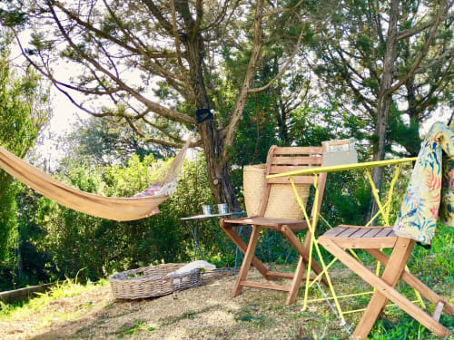 Outdoor seating area at Villas Marincelu with hammock, wooden chairs, and table beneath shaded trees in Serra di Ferro