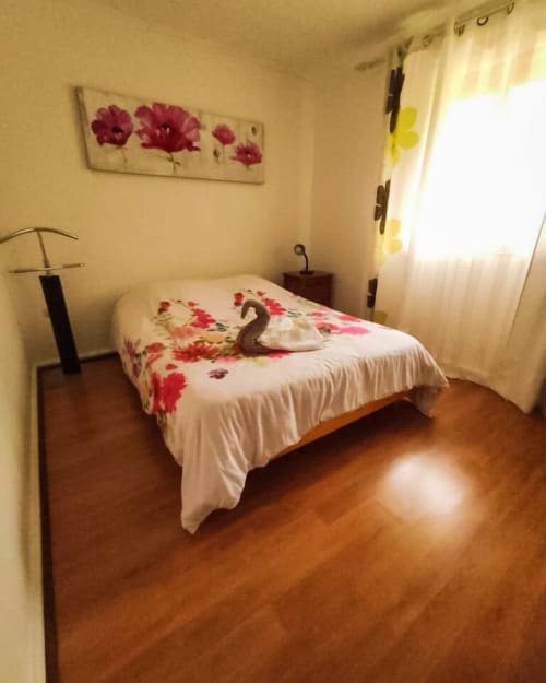 Chambre chaleureuse du gîte Les Terrasses Du Volcan avec couvre-lit fleuri, parquet et vue montagne à Le Tampon, Réunion