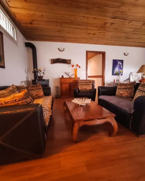 Séjour chaleureux au plafond bois, mobilier cuir, table orange et vue montagne au gîte Les Terrasses Du Volcan