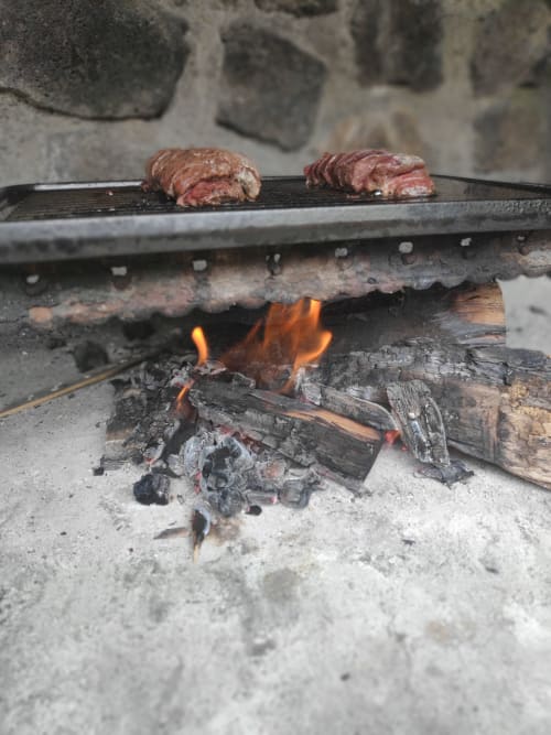 Steaks grillés cuits sur un feu de camp dans une assiette en fonte noire au gîte Les Terrasses Du Volcan à Tampon