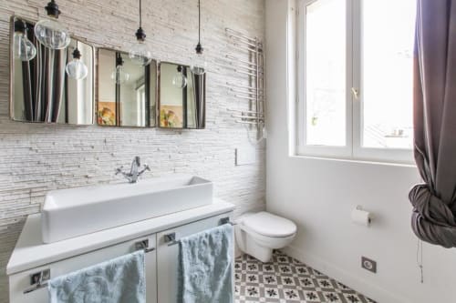 Modern bathroom at Montmartre Romantic B&B Paris with white vessel sink, mirrors, pendant lights, and patterned floor tiles