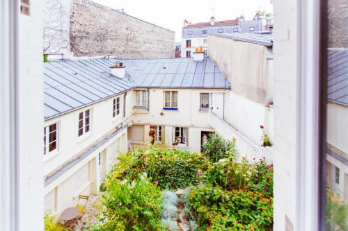 Parisian courtyard garden view from Grande Chambre at Montmartre Romantic B&B, with blooming flowers and classic Haussmann