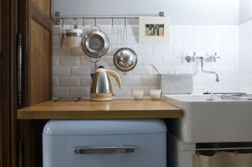 Petite cuisine de l'appartement Le Matelot aux Filles du Bord de Mer avec bouilloire crème, ustensiles suspendus et carrelage métro blanc