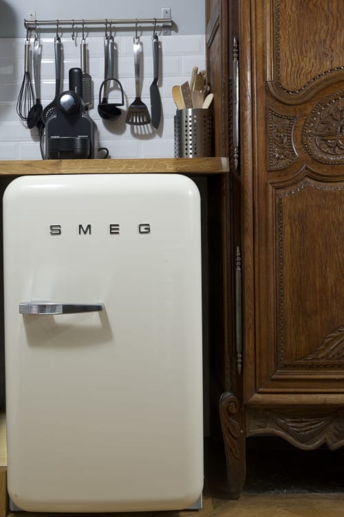 Réfrigérateur rétro SMEG crème dans une cuisine avec ustensiles suspendus et meubles en bois à l'appartement Les Filles du Bord de Mer