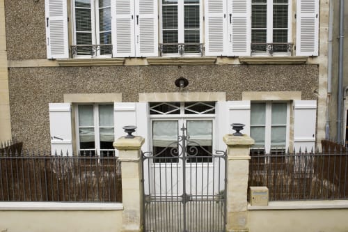 Façade de style parisien classique de l'hôtel Les Filles du Bord de Mer à Port-en-Bessin, avec volets blancs et