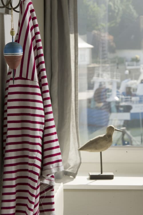 Fenêtre sur le port aux Filles du Bord de Mer avec rideaux rayés, décoration suspendue et canard décorativf