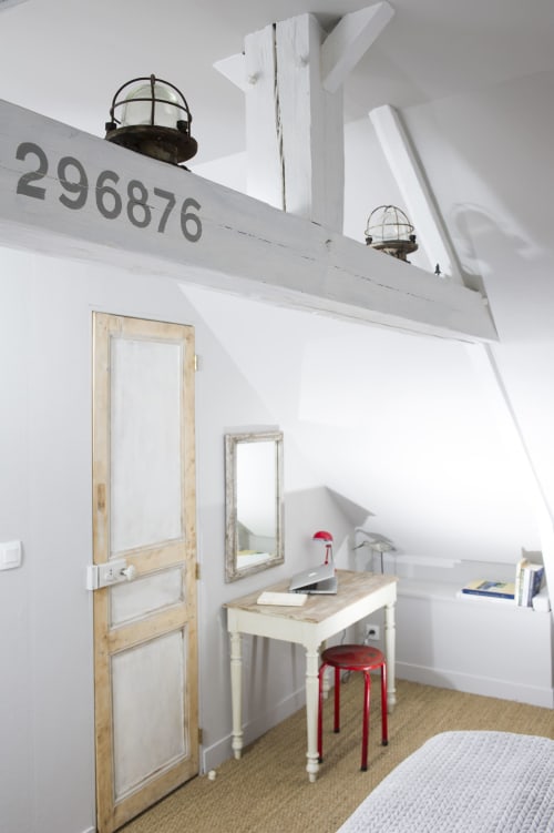 Chambre d'hôtel thématique nautique avec hublots lumineux, porte en bois, bureau avec tabouret rouge et vue sur le port aux Filles du