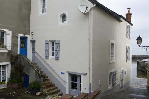 Crèmekleurig cottage met blauwe luiken en deur in de haven van Port-en-Bessin, Frankrijk
