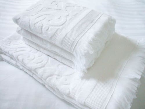 Stack of white folded towels with decorative pattern at Montmartre Romantic Bed & Breakfast Paris