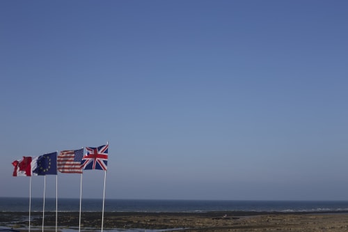 Quatre drapeaux internationaux flottant sur la plage des Filles du Bord de Mer à Port-en-Bessin-Huppain