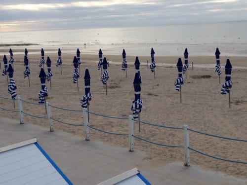 Rangées de parasols bleus et blancs sur la plage de Les Filles du Bord de Mer, Port-en-Bessin