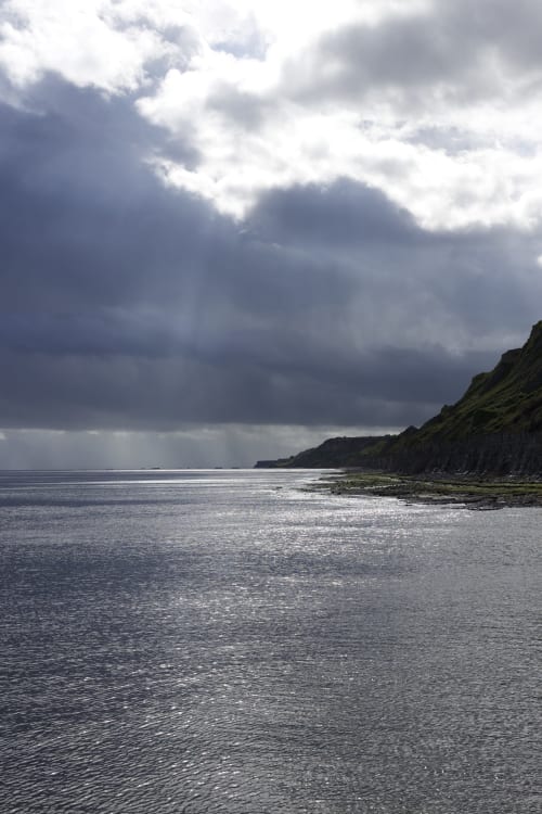 Côte dramatique aux falaises rocheuses sous un ciel nuageux à Port-en-Bessin, Normandie