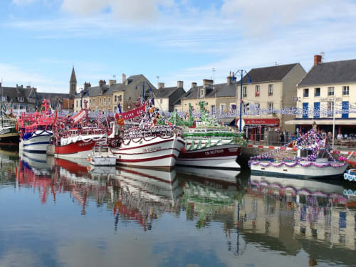 Bateaux de pêche colorés décorés pour la fête au port de Port-en-Bessin avec bâtiments côtiers