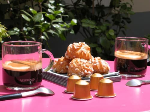Nespresso coffee service with pastries and orange capsules on pink table at Paris Montmartre B&B