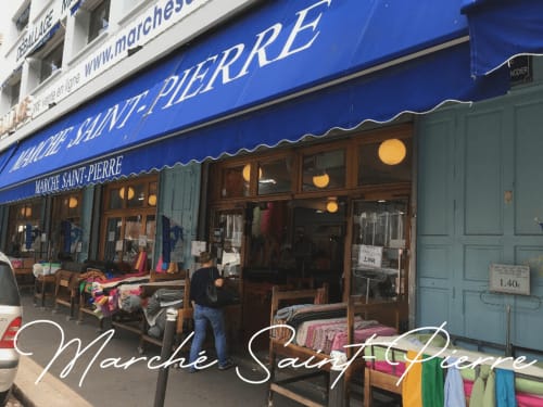 Marché Saint-Pierre storefront in Montmartre, Paris with blue awning and colorful fabrics displayed outside