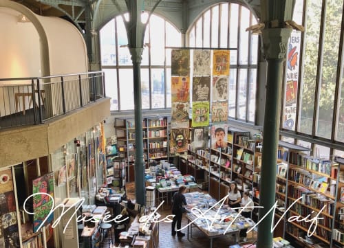 Musée des Nuits bookstore in Montmartre Paris with arched windows, bookshelves, and vintage posters