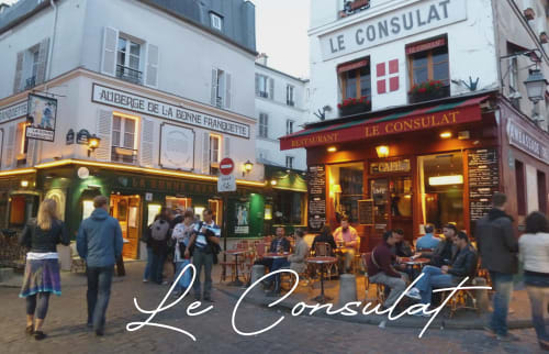 Le Consulat café in Montmartre, Paris with diners on terrace and historic Parisian buildings