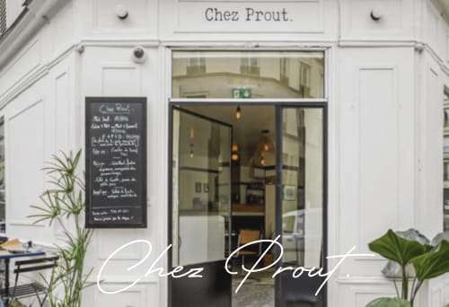 Chez Prout storefront in Montmartre Paris with white facade, black menu board, and glass entrance doors