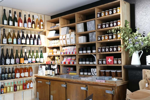 Étagères de boutique aux Filles du Bord de Mer présentant vins, confitures et produits locaux à Port-en-Bessin
