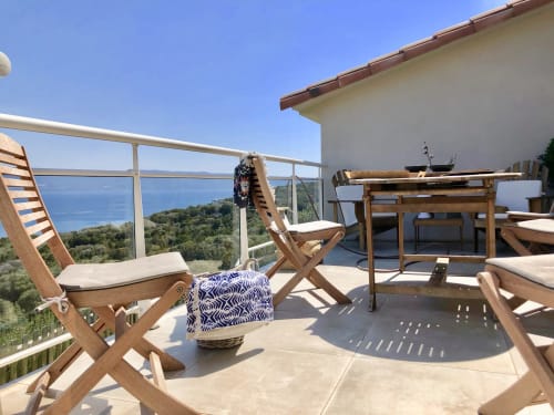 Sunny terrace at Villas Marincelu with wooden loungers overlooking Mediterranean sea and Corsican coast, Serra di Ferro