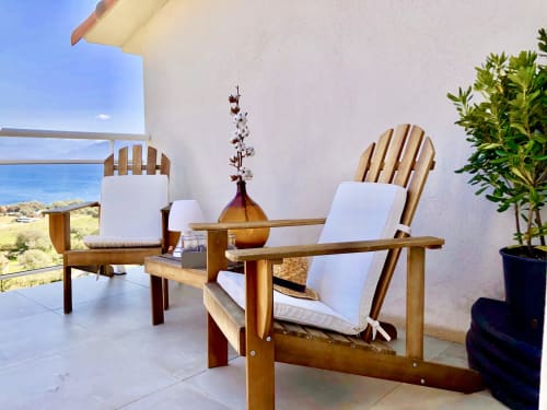 Wooden Adirondack chairs with white cushions on a terrace at Villas Marincelu, Porto Pollo, overlooking Mediterranean coastal