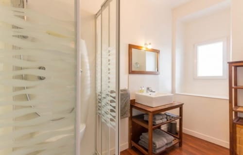 Salle de bain moderne avec douche italienne, meuble vasque en bois et miroir au gîte Les Filles du Bord de Mer à Port-en-Bessin