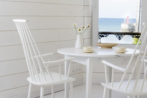 Helles Esszimmer mit zwei Stühlen und rundem Tisch mit Gänseblümchen, Teetassen und Hafenblick bei Les Filles du Bord de