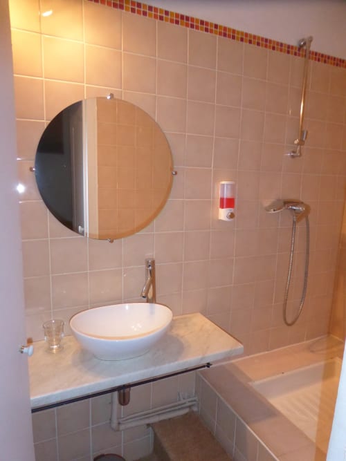 Bagno moderno al Domaine de Lamartine con specchio rotondo, lavabo bianco e doccia a Pont-Saint-Esprit
