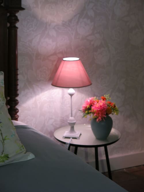 Elegante lampada da comodino con paralume rosa su tavolo rotondo accanto a fiori freschi al Domaine de Lamartine B&B, Pont-Saint-Esprit