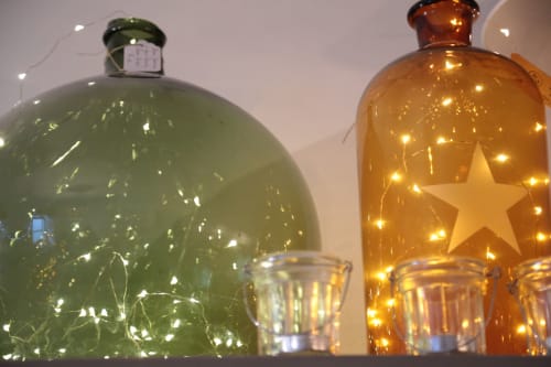 Décoration festive aux Filles du Bord de Mer : bouteilles de verre illuminées aux étoiles et lumières chaleureuses